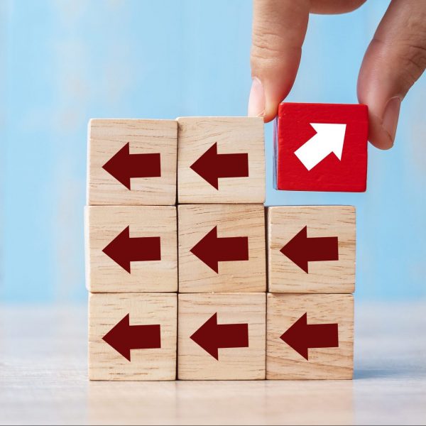 Businessman hand placing or pulling Red block with different direction of arrow on table background. Business Growth, Improvement, strategy, Successful, different and Unique Concepts